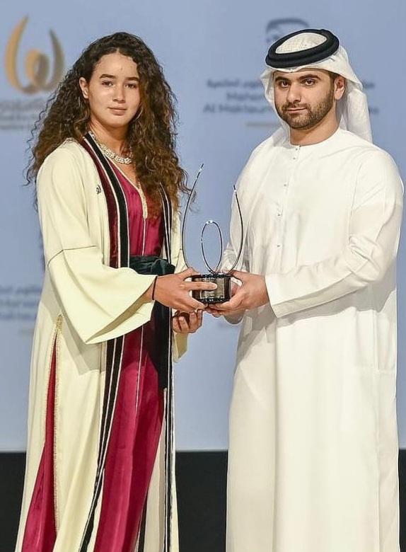 Malak, en caftan marocain traditionnel, reçoit son trophée.